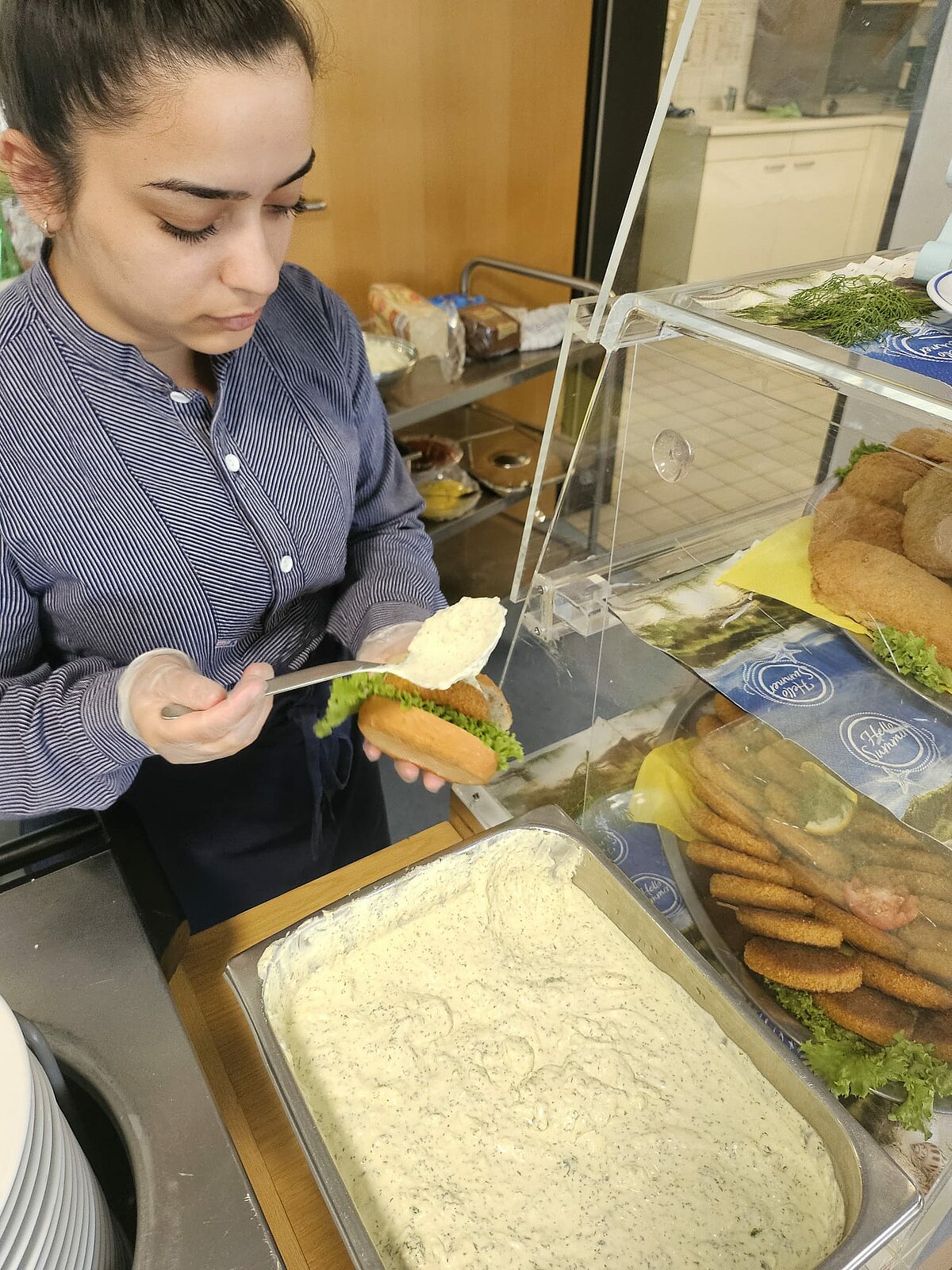 Fischbrötchen werden mit Sauce bestrichen