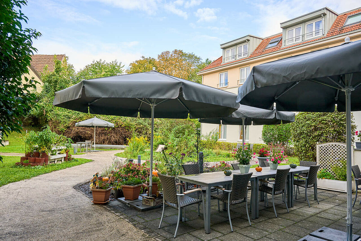 Terrasse mit großem Tisch und Sonnenschirmen