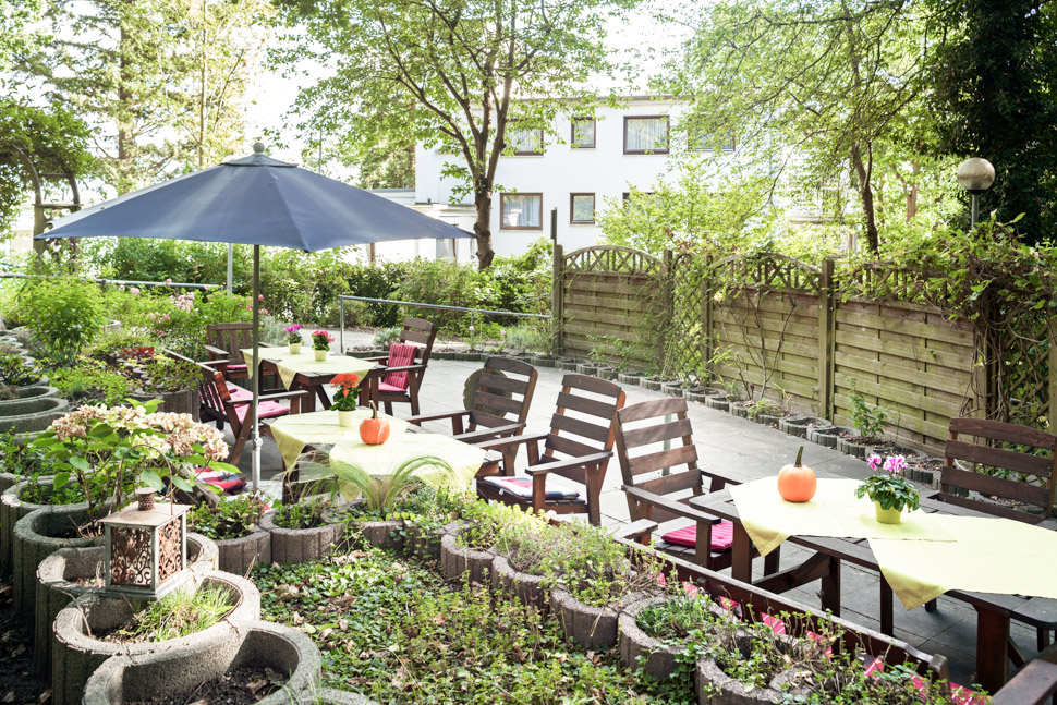 Terrasse mit Tischen und Stühlen vor der Alloheim Senioren-Residenz Godenbergschlößchen in Bad Malente