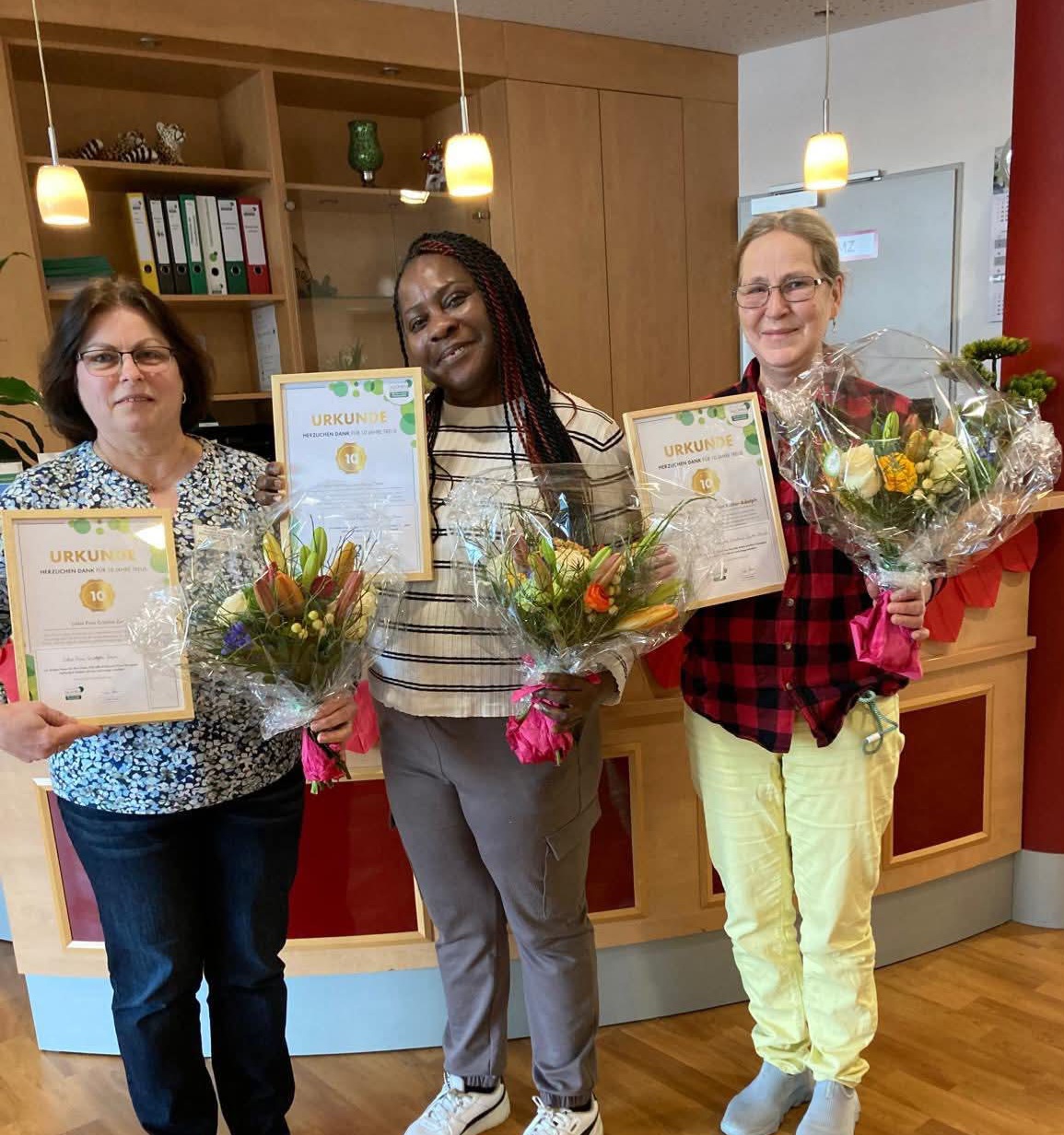 Mitarbeiter mit Blumen und Urkunden